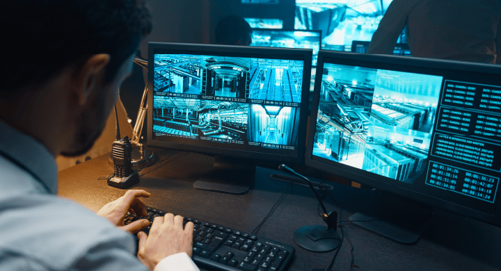 Security guard monitors camera feeds in a data center on dual monitors