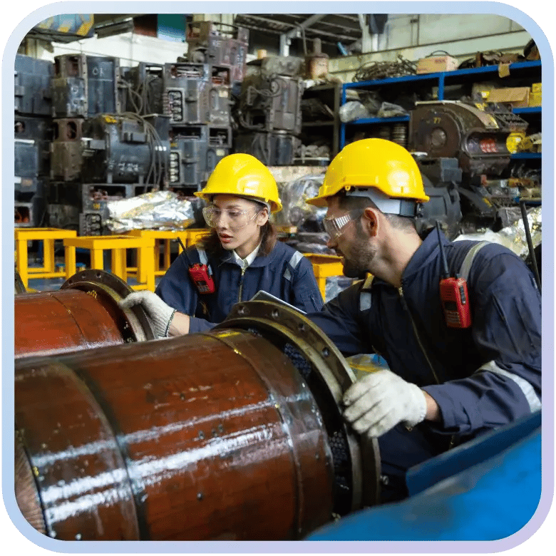 Manufacturing workers inspect large pipes will wearing safety gear.